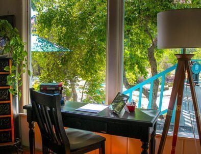 A black wooden desk stands ready for the arrival of a guest seeking writing inspiration from the garden and river view through this picture window.